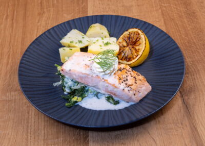 Mittagessen für Firmen mit hochwertigen Lebensmitteln und einfacher Zubereitung - Beispielbild: Lachs mit Petersilkartoffeln auf Grüngemüse
