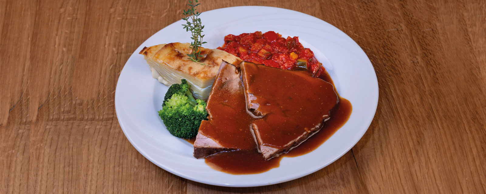 Mittagessen für Firmen mit hochwertigen Lebensmitteln und einfacher Zubereitung - Beispielbild: Braten mit Letscho und Kartoffelgratin